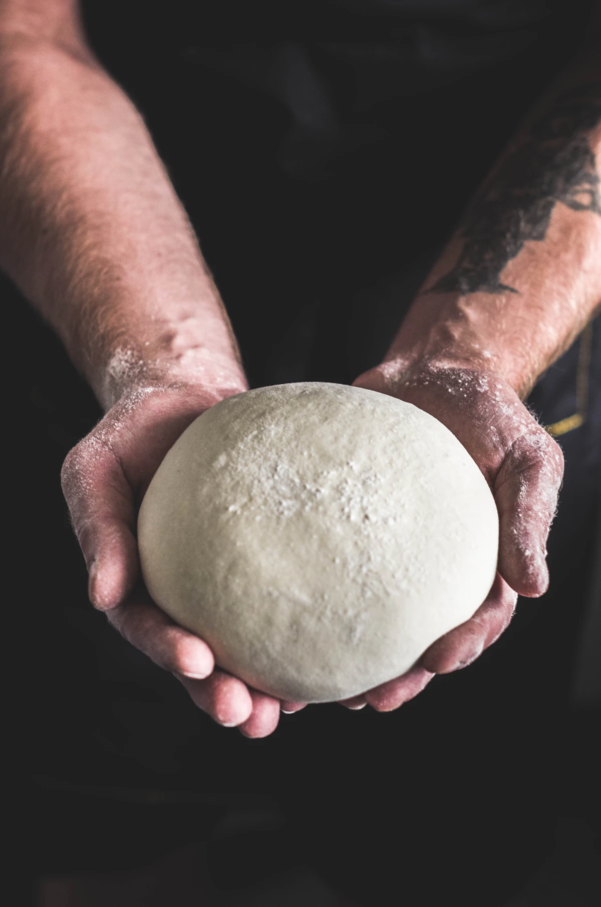 Flour-dusted hands holding a ball of dough
